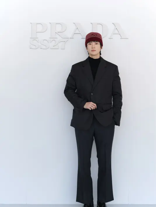 Jaehyun kenakan setelan jas oversized hitam. Dipadukan kaus turtleneck hitam dan topi kupluk rajut merah marun, serta boots hitam [dok. Prada]