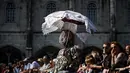 Seorang wanita dari Madamas e Caretos de Torre de Dona Chama mengenakan kostum dan membawa payung saat mengikuti International Festival of the Iberian Mask ke-12 di Belem, Lisbon, Portugal (5/6). (AFP Photo/Patricia De Melo Moreira)