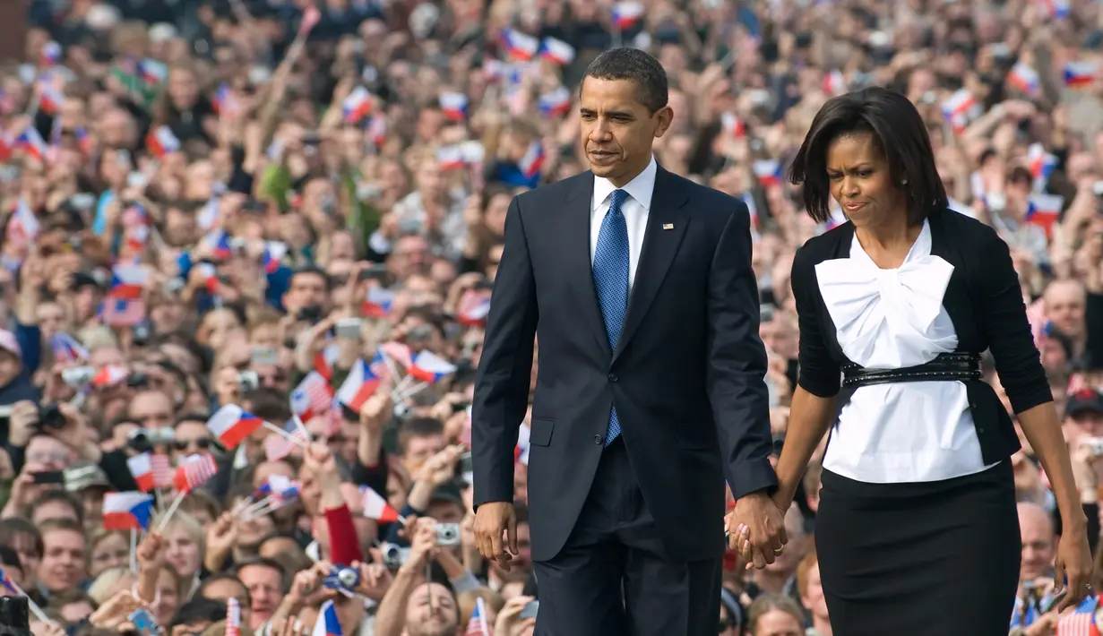 Presiden Amerika Serikat (AS) ke-44, Barack Obama menggandeng tangan sang istri, Michelle Obama, saat berjalan menuruni podium usai menyampaikan pidato di Hradcany Square, dekat Kastil Praha Republik Ceko, 5 April 2009. (AFP PHOTO / SAUL LOEB)