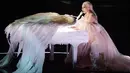 Lady Gaga tampil dan bermain piano. Sayap malaikat yang menghisi alam musiknya itu pun menambah syahdunya suasana. (KEVIN WINTER / GETTY IMAGES NORTH AMERICA / AFP)