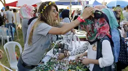Seorang pengunjung saat dipakaikan hiasan dikepalanya saat mengunjungi festival memperingati Hari Perdamaian Internasional di Baghdad, Irak (21/9/2015). Perayaan diisi dengan kreativitas seni karya para pemuda dan pemudi Irak. (REUTERS/Thaier al-Sudani)