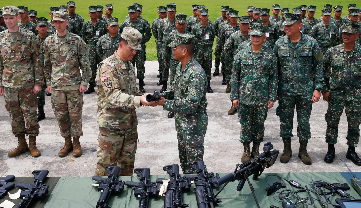 Komandan Korps Marinir Filipina, Mayjen Emmanuel Salamat menerima senapan M4 dengan peluncur granat dari Kolonel AS, Kolonel Ernest Lee di kota Taguig, sebelah timur Manila, Filipina (5/6). (AP Photo / Bullit Marquez)