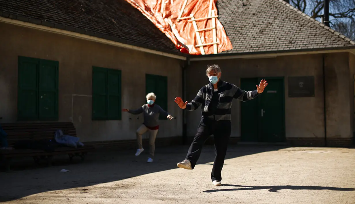 Orang-orang mengenakan masker untuk mencegah penyebaran COVID-19 saat berlatih Tai Chi di Taman Cinquantenaire, Brussel, Belgia, Senin (29/3/2021). Pemerintah Belgia akan menutup sekolah dan membatasi akses warga ke bisnis yang tidak penting selama lockdown ketat COVID-19. (AP Photo/Francisco Seco)