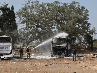 Seorang petugas pemadam kebakaran Israel memadamkan bangkai bus di lokasi jatuhnya rudal Iran di sebuah depot bus di Herzliya dekat Tel Aviv pada 17 Juni 2025. (Jack GUEZ/AFP)
