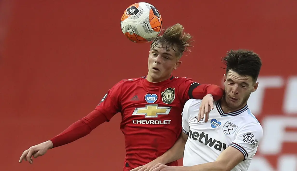 Pemain Manchester United, Brandon Williams, duel udara dengan pemain West Ham United, Declan Rice, pada laga Premier League di Stadion Old Trafford, Rabu (22/7/2020). Kedua tim bermain imbang 1-1. (Martin Rickett/Pool via AP)