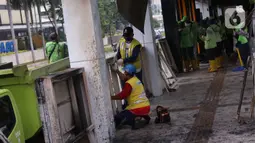 Sejumlah petugas membersihkan sisa kerusakan Halte Bus TransJakarta Tosari, Jakarta, Jumat (9/10/2020). Sejumlah fasilitas umum rusak dalam kericuhan unjuk rasa menolak pengesahan UU Cipta Kerja yang terjadi Kamis (8/10).  (Liputan6.com/Angga Yuniar)