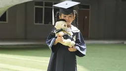 Ruben dan Sarwendah tetap kompak mendukung perjalanan pendidikan anak-anak mereka. Di momen bahagianya, Thania tampil menggemaskan dengan pakaian toga, lengkap dengan topinya. Gadis kecil berusia 5 tahun itu mendekap boneka beruang hadiah kelulusannya. (Liputan6.com/IG/@ruben_onsu)