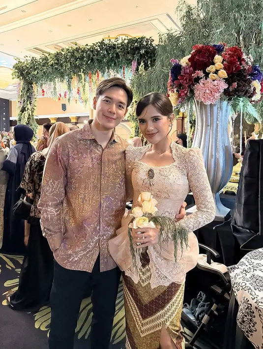 Pasangan Audi Marissa dan Anthony Xie juga tampil kompak dengan warna-warna lembut yang elegan. Audi mengenakan kebaya bridesmaid berwarna nude rancangan desainer Renzi Lazuardi. Kebaya ini memiliki detail kerah u-neck, lengan bahu puffed, serta aksen draped di bagian pinggang yang memberikan siluet menawan. [@audimarissa]