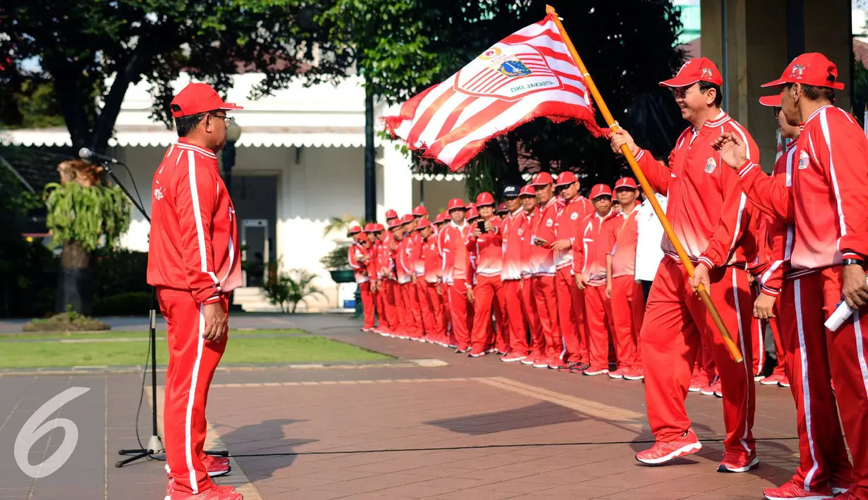 Gubernur DKI Jakarta, Basuki Tjahaja Purnama (kedua kanan) menyerahkan bendera kontingen kepada ketua tim yang akan berlaga di PON XIX Jabar di halaman Balaikota Jakarta, Rabu (7/9). DKI Jakarta menerjunkan 1.258 atlet. (Liputan6.com/Helmi Fithriansyah)