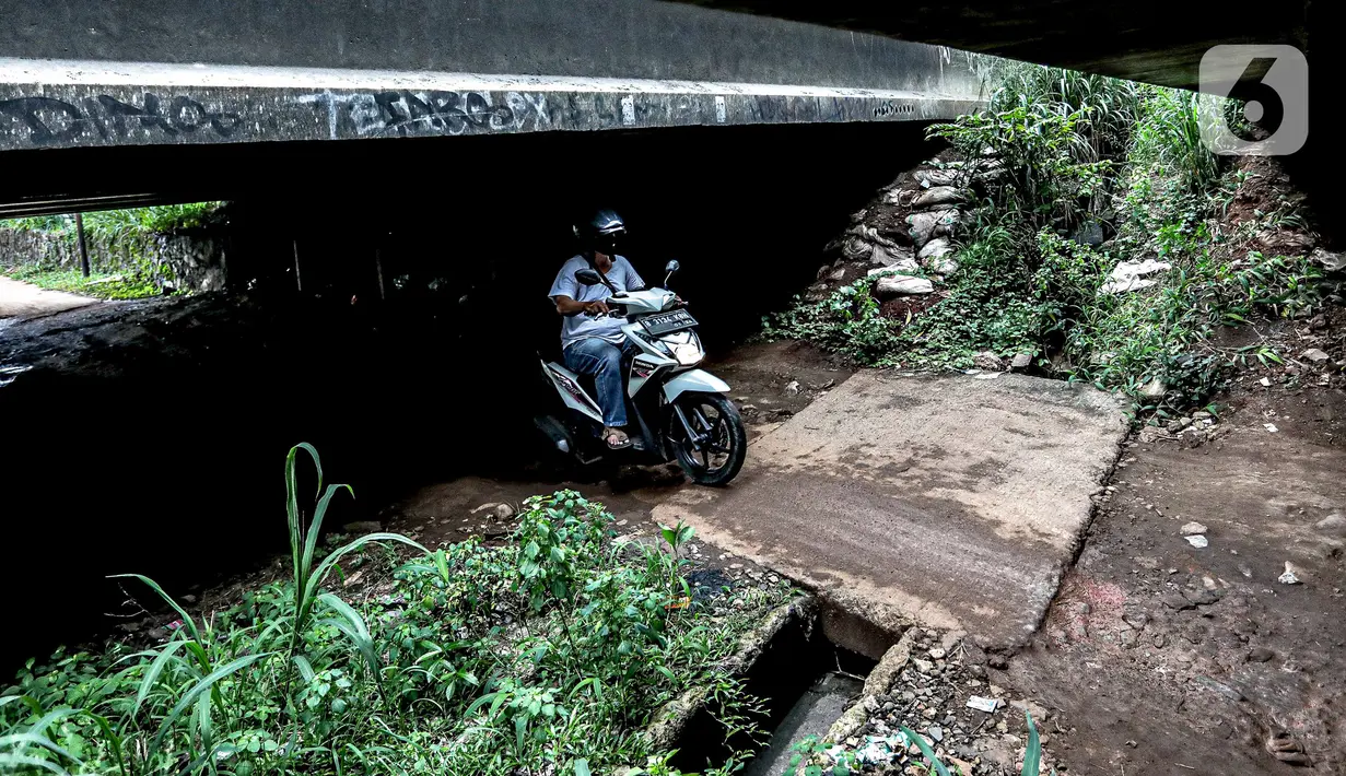 Pengendara sepeda motor melintas di kolong Tol Jagorawi, Cimanggis, Depok, Jawa Barat, Minggu (8/11/2020). Buruknya jalan dan minimnya penerangan membuat akses tersebut rawan aksi kejahatan. (Liputan6.com/Faizal Fanani)