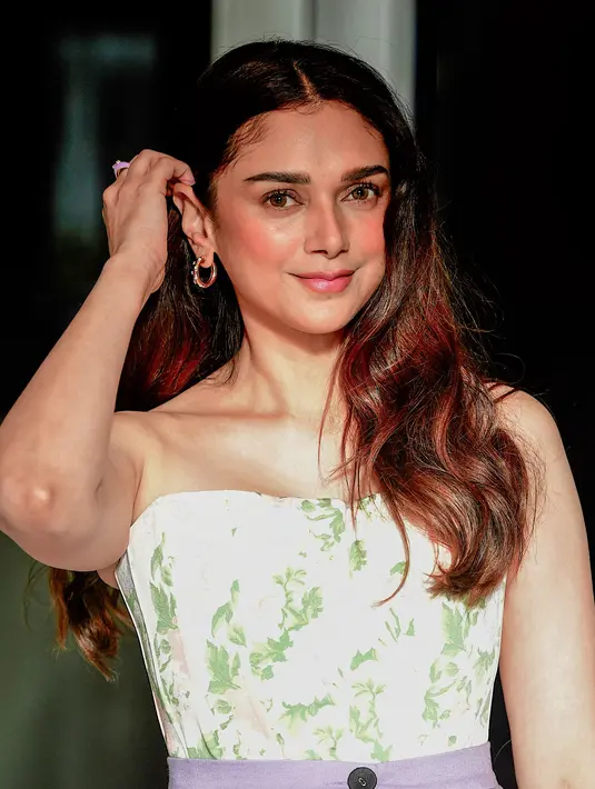 Aditi Rao Hydari merapikan rambutnya saat menghadiri peluncuran 'hyaluronic moisture range' L'Oréal Paris di Mumbai pada 25 Agustus 2022. Ia tampil cantik dengan busana bermotif bunga serta celana berwarna ungu. (AFP/Sujit Jaiswal)