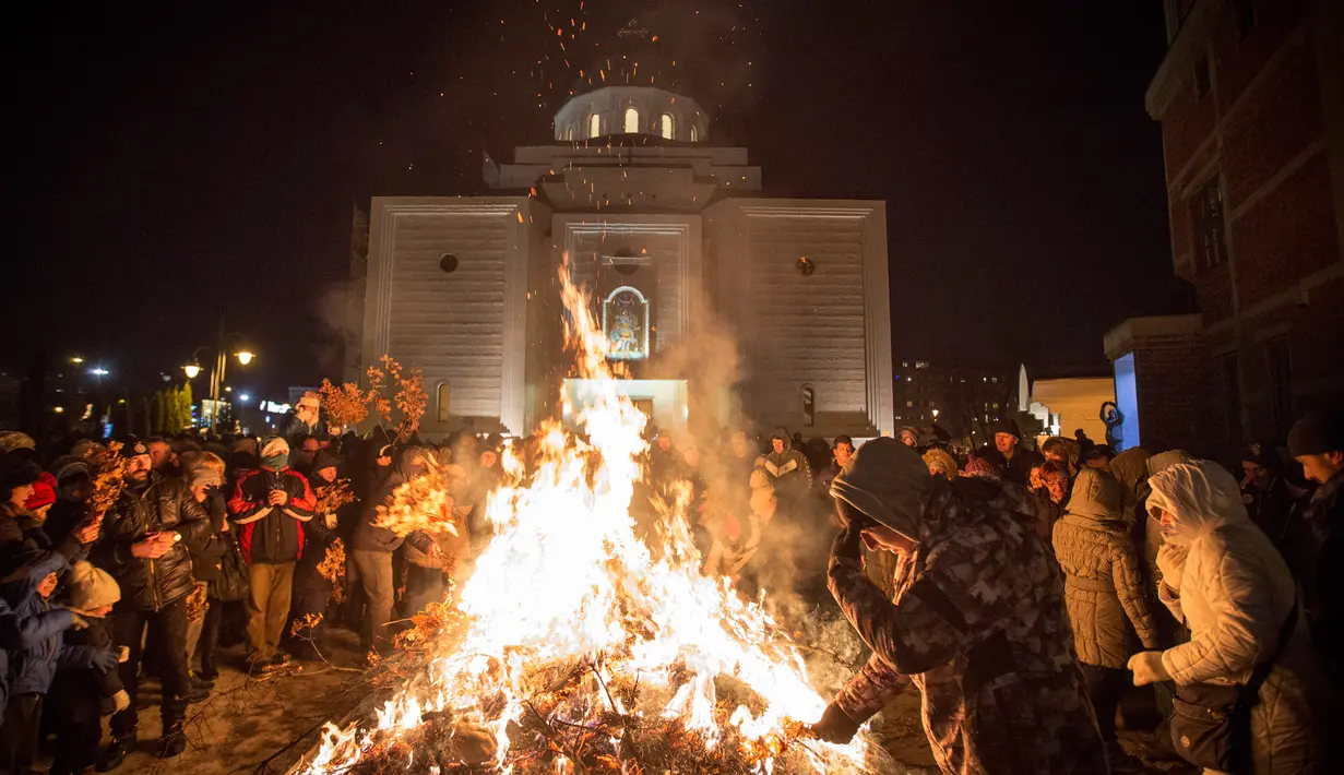 Sejumlah orang menghadiri upacara pembakaran cabang pohon oak kering  atau Yule log selama perayaan Hari Natal Ortodoks di Belgrade, Serbia (6/1). (AFP/Oliver Bunic)