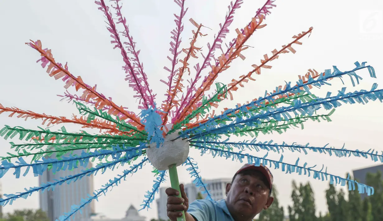 Pekerja menyelesaikan pembuatan kembang hiasan untuk diletakkan di atas kendaraan hias di kawasan Monas, Jakarta, Jumat (28/6/2019). Kendaraan hias tersebut dipersiapkan untuk Jakarnaval 2019 yang menjadi perayaan HUT ke-492 DKI Jakarta, Minggu (30/6). (Liputan6.com/Helmi Fithriansyah)