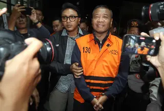 Bupati Tulungagung, Gatut Sunu Wibowo (tengah) dibawa petugas menuju mobil tahahan usai menjalani pemeriksaan intensif di Gedung Merah Putih Komisi Pemberantasan Korupsi (KPK), Jakarta, Minggu (12/4/2026) dini hari WIB. Komisi Pemberantasan Korupsi (KPK) resmi menahan Bupati Tulungagung, Gatut Sunu Wibowo beserta ajudannya, Dwi Yoga Ambal. (Liputan6.com/Helmi Fitrhiansyah)