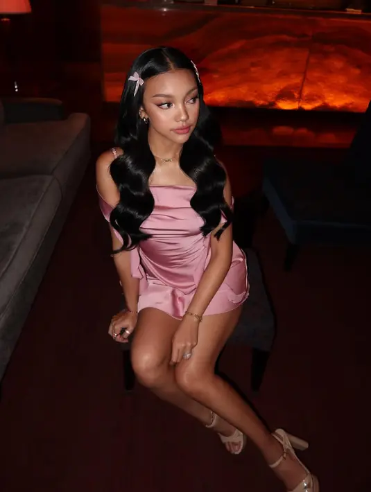 Gaun berwarna dusty pink yang ia kenakan merupakan rancangan @missmodern.id, label lokal yang dikenal dengan siluet modern dan feminin. Potongan asimetris, detail drapery, serta aksen ruffle di sisi rok memberi sentuhan glamor sekaligus lembut, mewakili keanggunan seorang Barbie versi masa kini.  [@naura.ayu].