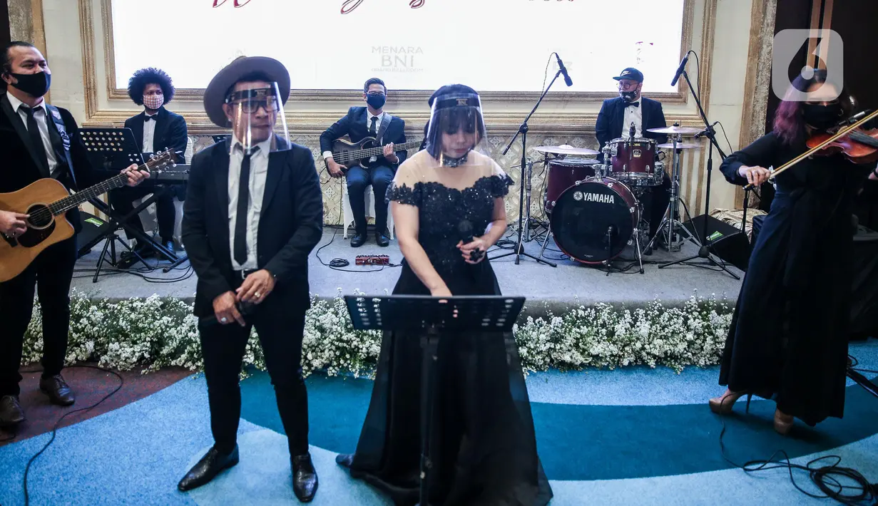 Band pernikahan mengenakan face shield saat simulasi penerapan protokol kesehatan resepsi pernikahan di era new normal di Jakarta, Kamis (9/7/2020). Kegiatan ini bertujuan untuk mengedukasi masyarakat dalam acara pernikahan guna mencegah penyebaran COVID-19. (Liputan6.com/Faizal Fanani)