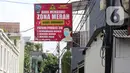 Warga melintasi spanduk zona merah kawasan RW 01 Kelurahan kalibata, Jakarta, Selasa (9/2/2021). Pemerintah mulai menerapkan PPKM skala mikro mulai 9-22 Februari 2021 untuk 7 provinsi yakni DKI Jakarta, Jawa Barat, Banten, Jawa Tengah, Yogyakarta, Jawa Timur, dan Bali. (Liputan6.com/Herman Zakharia)