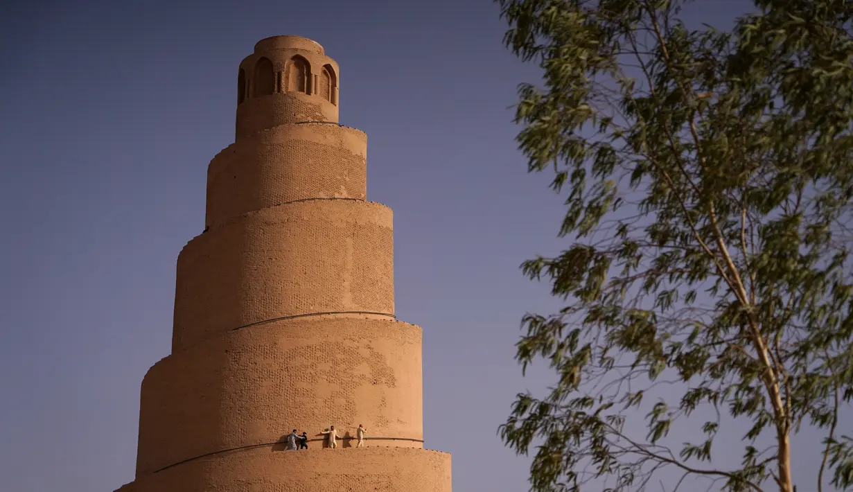 <p>Warga Irak berjalan di menara spiral Malwiya, monumen nasional Irak yang berharga pada pertengahan abad kesembilan, di dalam Kota Arkeologi Samarra, di Samarra, utara Baghdad (26/7/2022). Menara helikoid 50m dari batu bata yang dikeringkan dan dipanggang dengan sinar matahari, mencontoh ziggurat kuno yang dibangun untuk melambangkan kekuatan Islam selama kekhalifahan Abbasiyah, terdaftar sebagai Situs Warisan Dunia UNESCO pada tahun 2007. (AFP/Ismael Adnan)</p>