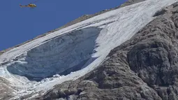 Helikopter penyelamat terbang di atas gletser Punta Rocca yang runtuh dekat Canazei di Pegunungan Alpen Italia di Italia utara (4/7/2022). Tim penyelamat mengatakan kondisi lereng bawah dari gletser, yang telah mencair selama beberapa dekade, masih terlalu tidak stabil. (AP Photo/Luca Bruno)