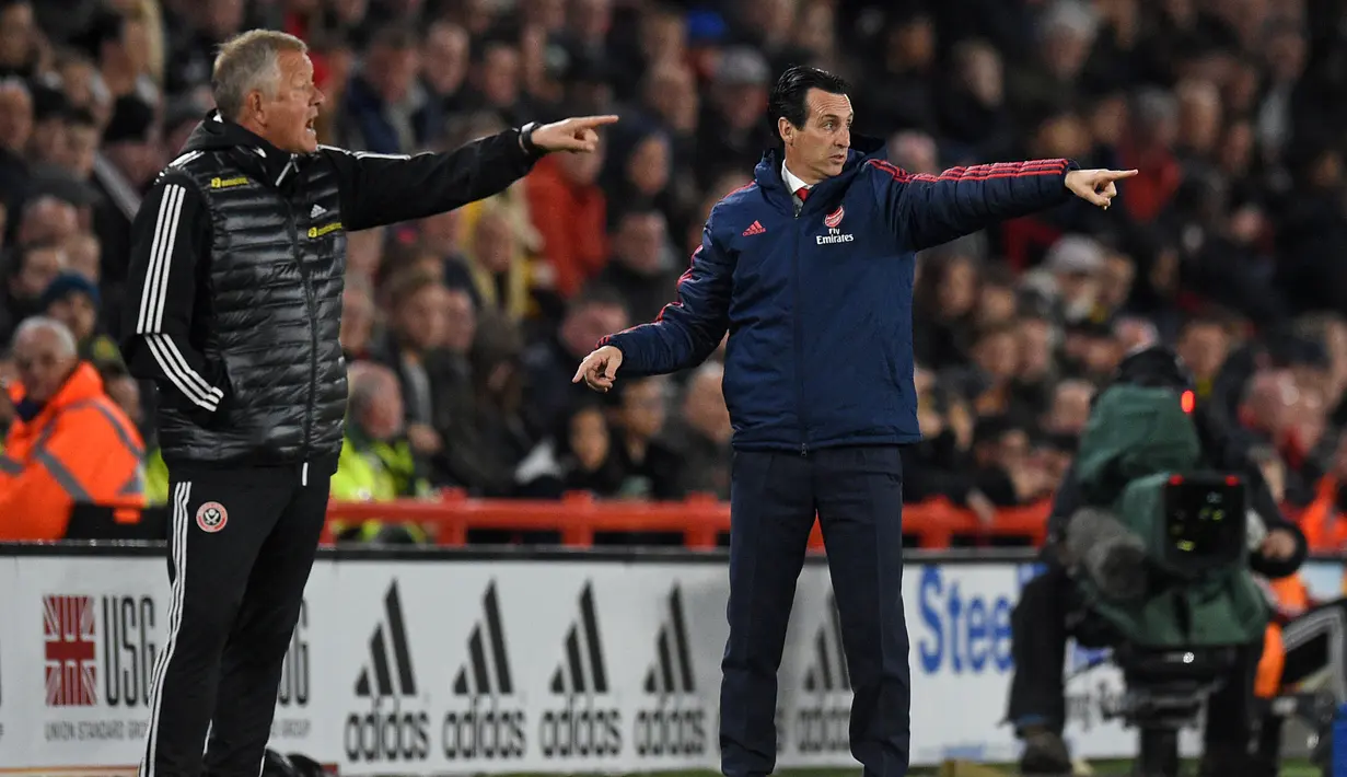 Pelatih Sheffield United Chris Wilder (kiri) dan pelatih Arsenal Unai Emery (kanan) memberi arah dari tepi lapangan saat anak asuh mereka bertanding pada pertandingan Liga Inggris di Bramall Lane, Sheffield, Inggris, Senin (21/10/2019). Sheffield United menang1-0. (Oli SCARFF/AFP)