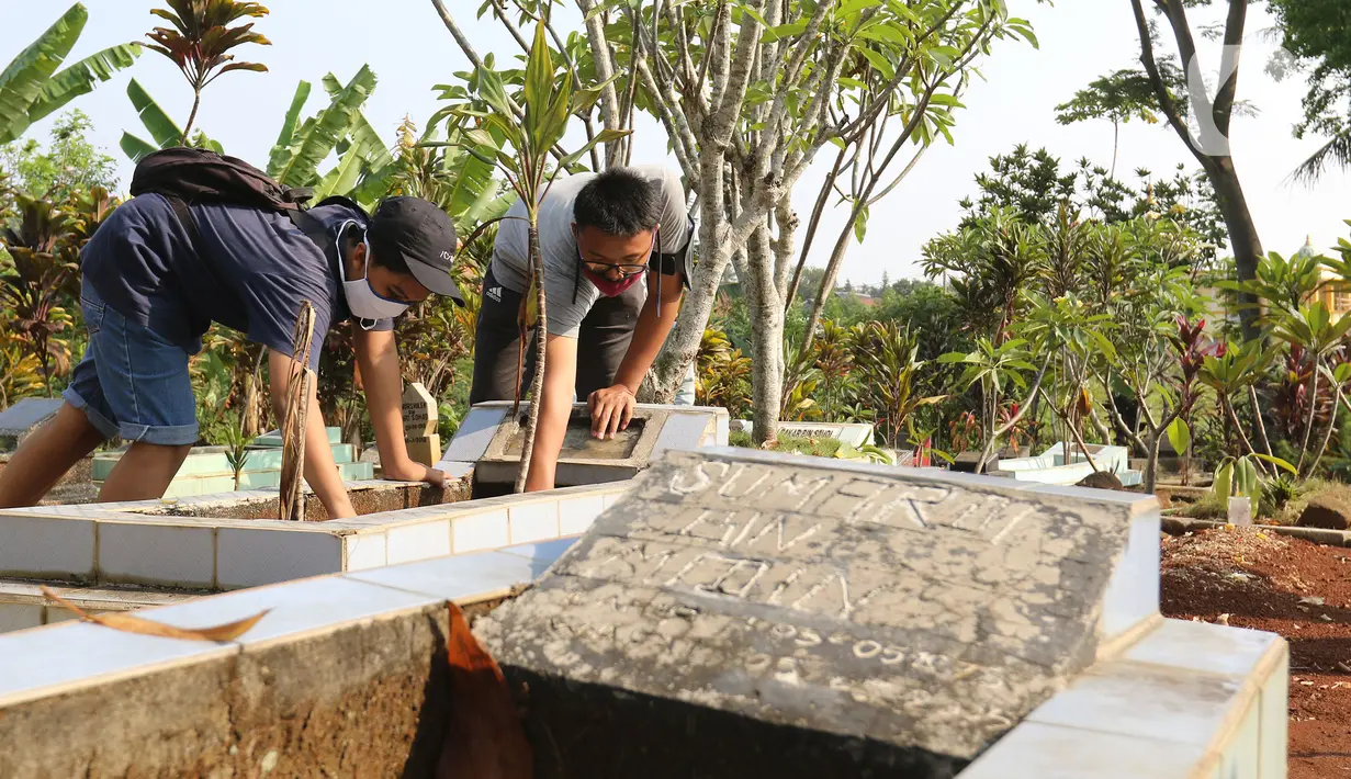 Pelanggar PSBB dihukum membersihkan makam di kawasan Stadion Pakansari, Kabupaten Bogor, Minggu (6/9/2020). Pemkab Bogor menghukum pelanggar PSBB dengan denda Rp 100 ribu serta sanksi sosial seperti membersihkan area makam, push up, dan mempraktikkan prosesi pemakaman. (Liputan6.com/Herman Zakharia)