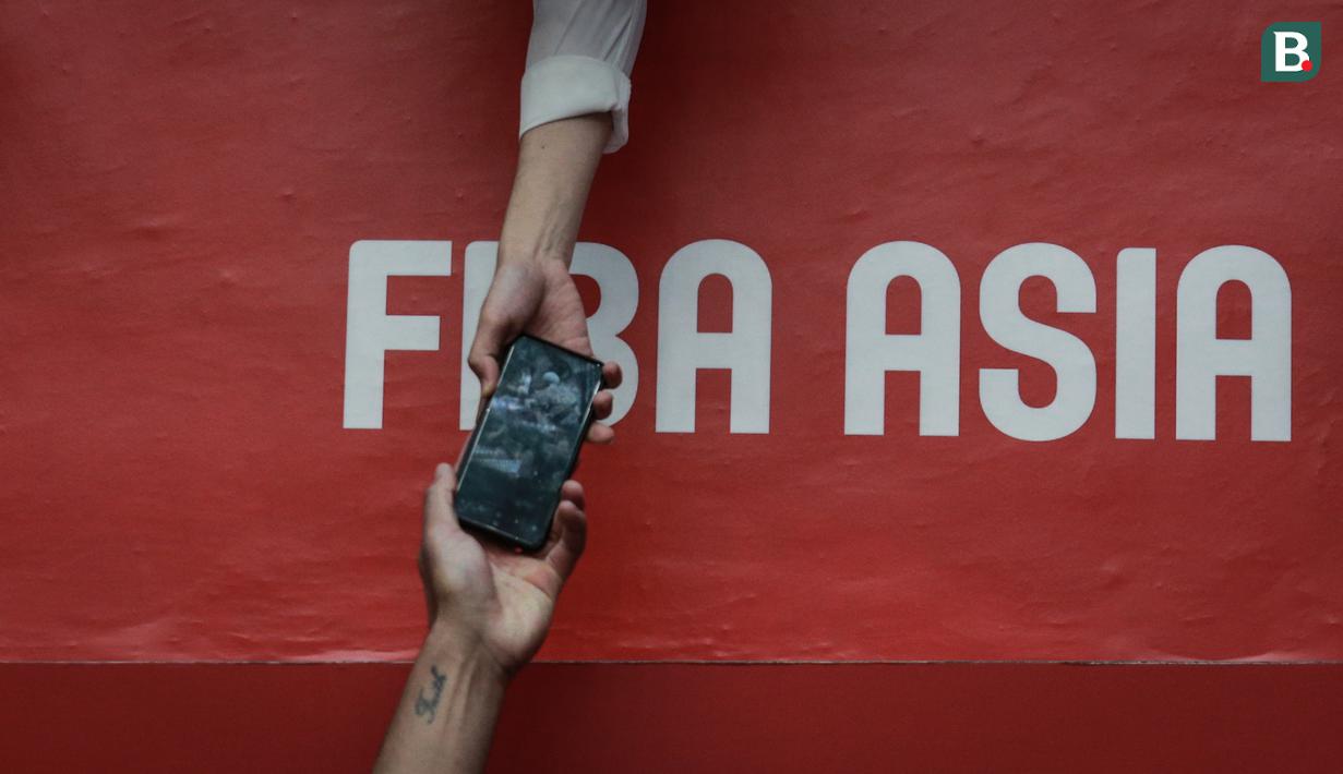 Seorang penonton memberikan handphone miliknya ke pemain Timnas Basket Selandia Baru, Flynn Cameron untuk melakukan swafoto bersama usai laga perempat final FIBA Asia Cup 2022 antara Korea Selatan melawan Selandia Baru pada Kamis (21/07/2022) di Istora Senayan, Jakarta. (Bola.com/Bagaskara Lazuardi)