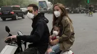 Sebuah keluarga mengendarai motor sambil mengenakan masker saat badai debu menerjang kota Beijing, China, Kamis (4/5). Imbas dari badai tersebut, jarak pandang di Beijing turun drastis hingga satu kilometer, di pagi hari. (Nicolas ASFOURI/AFP)