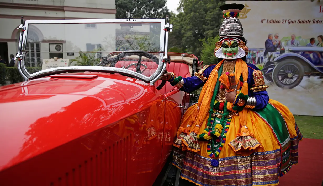 Penari berpose dengan mobil vintage yang baru direstorasi dalam pameran 21 Gun Salute Heritage and Cultural Trust di New Delhi, India, Selasa (6/2). (AP Photo/Altaf Qadri)
