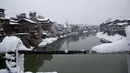 Salju yang menyelimuti rumah-rumah di sepanjang Sungai Jhelum di Srinagar, Kashmir yang dikuasai India (7/1). Musim salju telah mengakibatkan gangguan lalu lintas udara dan lalu lintas jalan antara Srinagar dan Jammu. (AP Photo/Mukhtar Khan)