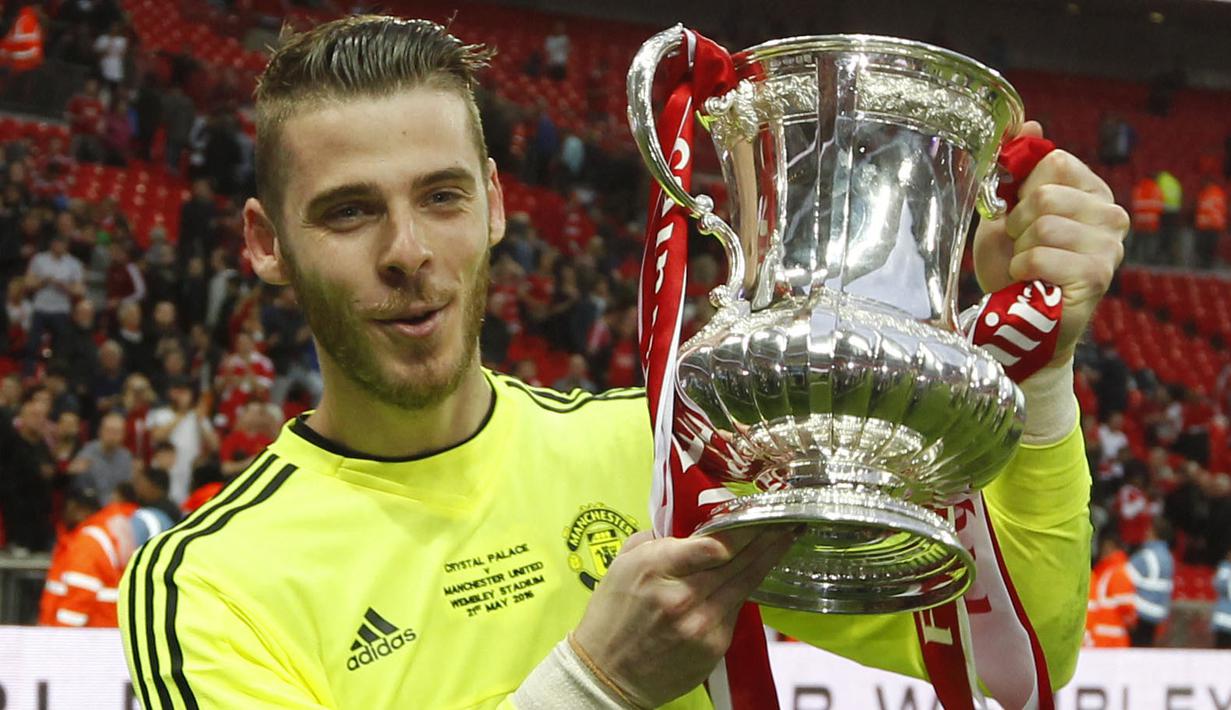 Pemain Manchester United, David de Gea berpose bersama trofi FA Cup setelah memenangkan laga final melawan Crystal Palace di Stadion Wembley, London, 21 Mei 2016. De Gea tercatat berhasil mempersembahkan satu trofi FA Cup selama 12 tahun berkarier di Manchester United. (AFP/Ian Kington)