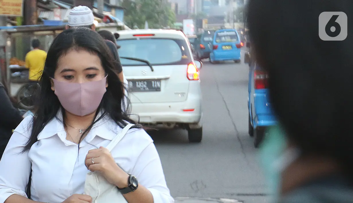 Warga mengenakan masker berjalan di Depok, Jawa Barat, Senin (2/3/2020). Dua pasien terjangkit corona yang dirawat di RSPI Sulyanti Saroso  merupakan warga Depok. Mendengar kabar yang diumumkan Presiden Jokowi membuat warga mulai mengantisipasi mengenakan masker. (Liputan6.com/Herman Zakharia)