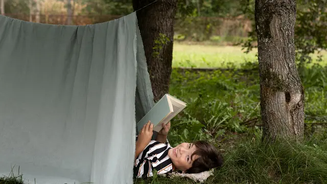 Ilustrasi anak membaca buku sambil tidur di tenda alam terbuka/freepik.com/pikisuperstar