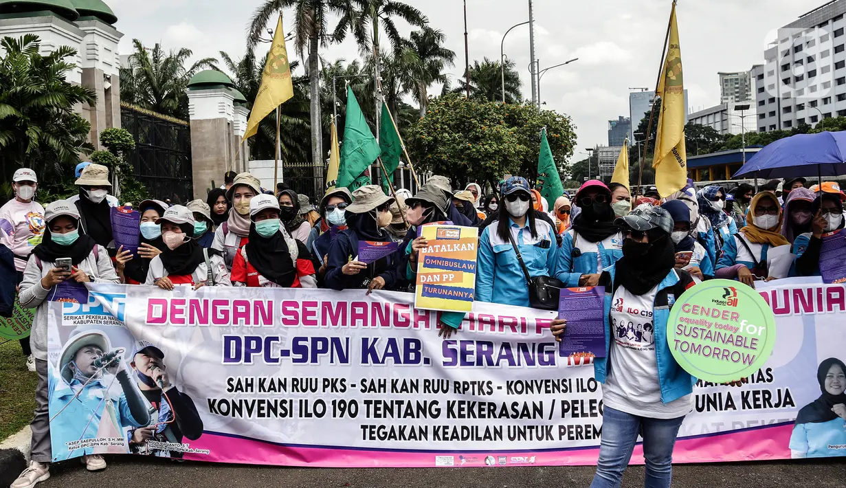Sejumlah buruh perempuan memegang poster saat menggelar aksi di depan gedung DPR RI, Jakarta, Selasa (8/3/2022). Mereka menuntut dibatalkannya Omnibus Law UU Cipta Kerja dan mendesak agar RUU Tindak Pidana Kekerasan Seksual (TPKS) segera disahkan oleh DPR RI. (Liputan6.com/Johan Tallo)