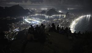 Para turis menunggu matahari terbit dari puncak Morro Dois Irmaos di atas favela Vidigal, sehari setelah operasi polisi di Rio de Janeiro, Brasil, pada 21 April 2026. (dok. Pablo PORCIUNCULA / AFP)