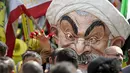 Max Saatchi bersama pengunjuk rasa lainnya sambil mengenakan topeng Presiden Iran Hassan Rouhani saat mengecam pelanggaran hak asasi manusia oleh pemerintah Rouhani di luar markas besar PBB, Manhattan, New York, AS (28/9/2015). (REUTERS/Darren Ornitz)