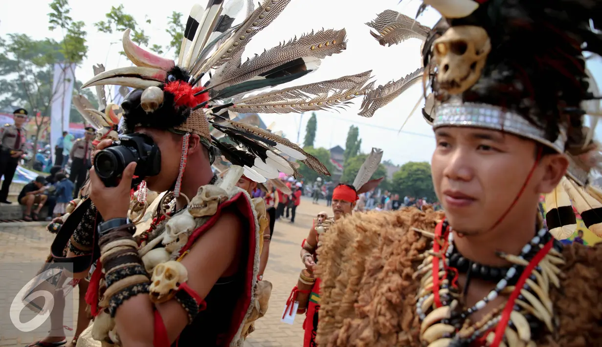 Seorang warga Suku Dayak Landak menngoperasikan kameranya saat festival Karnaval Katulistiwa di Pontianak, Kalimantan Barat, Sabtu (22/8/2015). (Liputan6.com/Faizal Fanani)