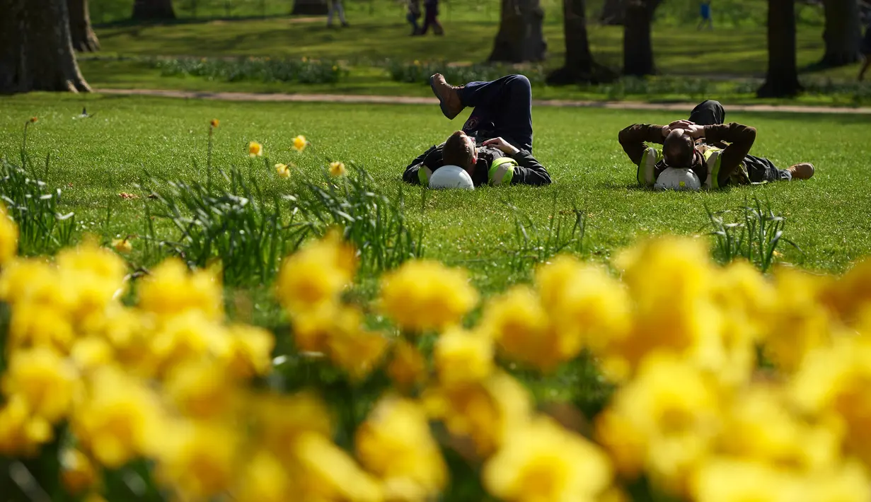 Dua orang pria berbaring di atas rumput sambil menikmati sinar matahari di sebuah taman di pusat kota London, Inggris, Rabu (4/5). Awal Mei, suhu udara hangat mulai menyelimuti kota London. (Niklas HALLE'N/AFP)