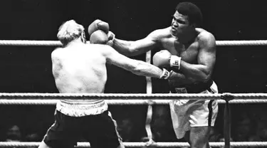 Muhammad Ali saat menghantam Richard Dunn dengan pukulan keras dalam turnamen WBC & WBA kelas berat di Munich, Jerman, (24/5/1976). Ali wafat pada usia 74 tahun dan dimakamkan di kota kelahirannya di Louisville, Kentucky. (REUTERS/Action Images/MSI)