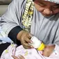 Warga menggendong bayi sambil memberi susu botol saat di Polsek Batuaji dan bayi ini ditemukan didalam koper di Perumahan Villa Paradise, Batuaji, Selasa (9/1). (Dalil Harahap/Batam Pos/Jawa Pos Group)