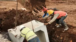 Pekerja memasang beton saluran air di proyek normalisasi Ciliwung, Bukit Duri, Jakarta, Rabu (8/2). Penyelesaian normalisasi Ciliwung mencakup pembangunan dinding parapet, sheetpile, jalan inspeksi maupun saluran air.(Liputan6.com/Yoppy Renato)