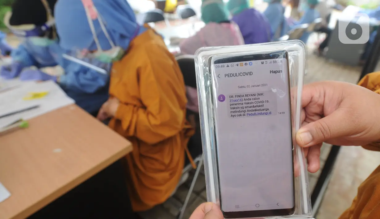 Paramedis menunjukkan SMS undangan vaksin Covid-19 di Puskesmas  Ciganjur, Jakarta Selatan, Kamis (7/1/2021). Pemerintah mulai menjalankan persiapan vaksinasi Covid-19 dengan mendata penerima tahap pertama setelah jutaan vaksin Covid-19 dari Sinovac tiba di Indonesia. (merdeka.com/Arie Basuki)