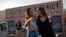 Dua penonton wanita tersenyum saat menghadiri Rock in Rio Festival di Olympic Park, Rio de Janeiro, Brazil, (22/9). Festival ini berlangsung  selama tujuh hari 15-17 September dan 21-24. (AFP Photo/Mauro Pimentel)