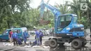 Petugas Sudin SDA Jakarta Timur dibantu alat berat membersihkan saluran gorong-gorong yang tertutup lumpur dan sampah di kawasan Pasar Rebo, Kamis (19/3/2020). Pembersihan untuk memperlancar sistem drainase yang tersumbat dan kerap menimbulkan genangan air. (Liputan6.com/Immanuel Antonius)