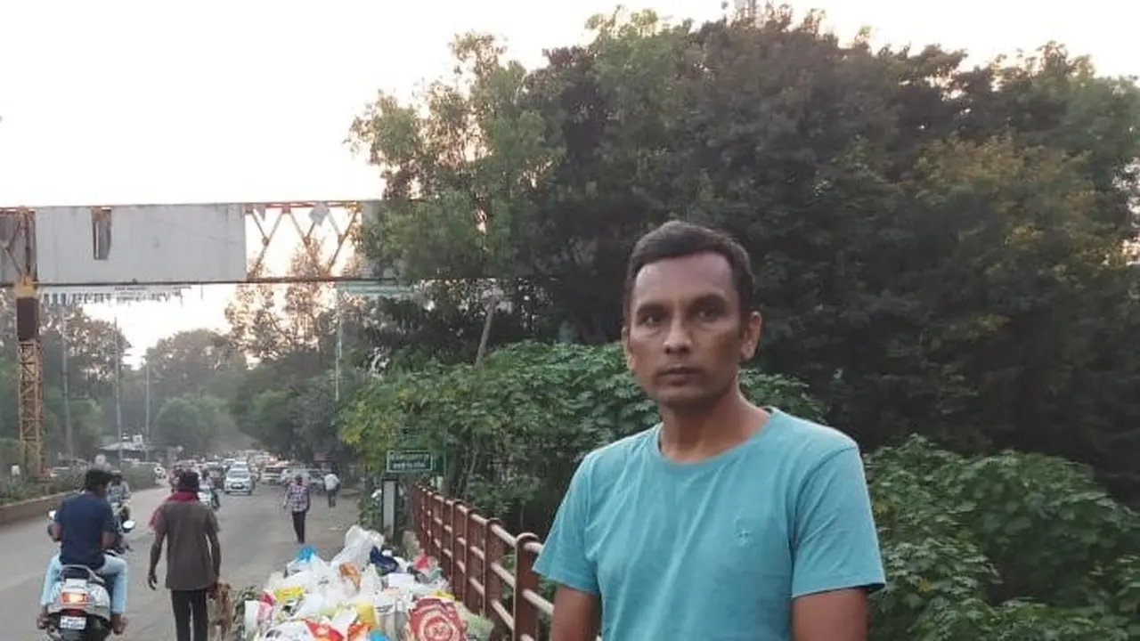 Chandra Kishore Patil berdiri di samping sungai Godavari India sambil membawa pluit untuk menghentikan para pembuang sampah plastik.