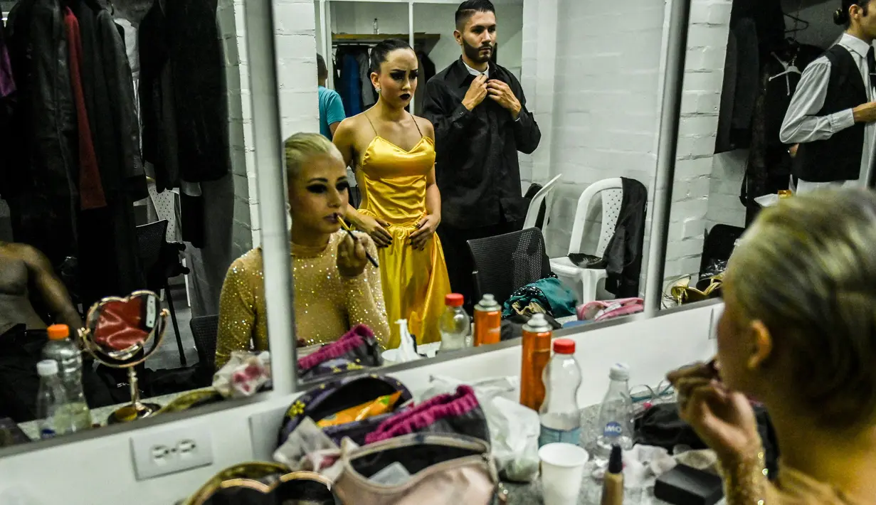 Penari menghias wajahnya di belakang panggun sebelum tampil dalam Turnamen Menari Tango di Festival Tango Internasional XIII di Medellin, Kolombia (18/6/2019). Festival Tango ini berlangsung dari 16 sampai 24 Juni 2019. (AFP Photo/Joaquin Sarmiento)