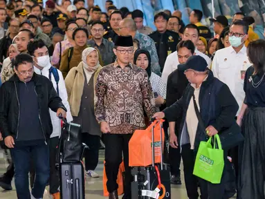 Menteri Luar Negeri Indonesia, Sugiono (tengah), berjalan bersama Warga Negara Indonesia yang kembali dari Iran tiba di Bandara Internasional Soekarno-Hatta, Tangerang, Banten, pada Selasa 10 Maret 2026. 22 Warga Negara Indonesia (WNI) yang dievakuasi dari Iran tiba di Indonesia melalui Bandara Internasional Soekarno-Hatta, Tangerang, Banten pada Selasa 10 Maret 2026. (BAY ISMOYO/AFP)