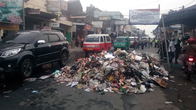 Tumpukan sampah dalam bak yang ditumpahkan warga ke jalan raya