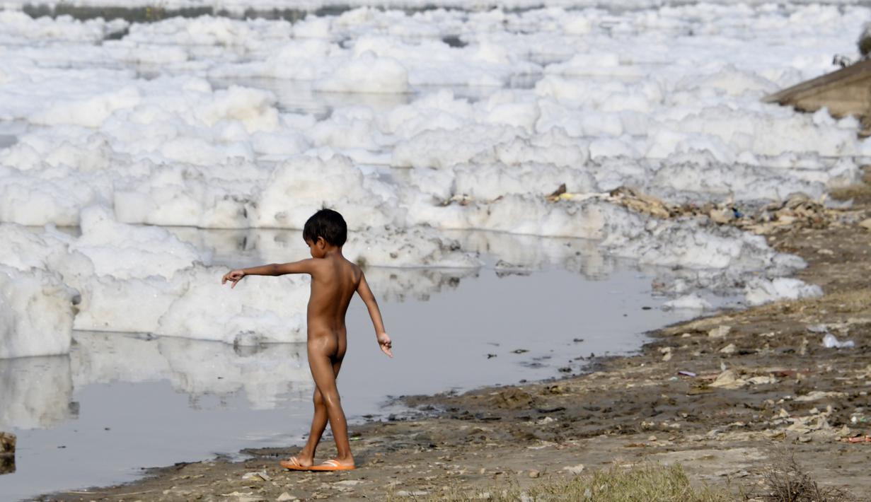 Seorang anak bermain di Sungai Yamuna yang tercemar di New Delhi, Sabtu (8/7). Akibat pertumbuhan populasi dan industrialisasi, Yamuna menjadi salah satu sungai paling tercemar di dunia. (DOMINIQUE FAGET / AFP)