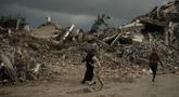 Warga Palestina berjalan melewati reruntuhan di tengah cuaca buruk Kota Gaza, Kamis 11 Desember 2025. Bencana baru mengancam ratusan ribu warga Palestina yang mengungsi di Jalur Gaza. (AP Photo/Jehad Alshrafi)