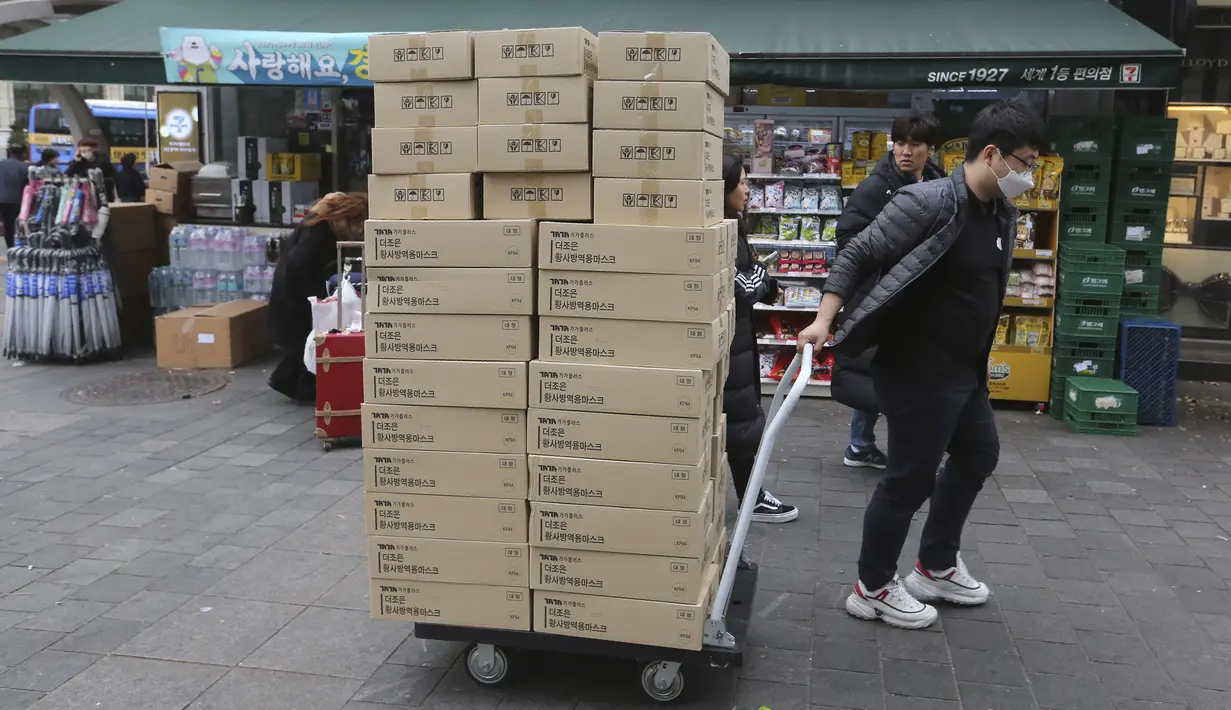 Seorang pekerja membawa kotak-kotak berisi masker ke apotek di sebuah distrik perbelanjaan di Seoul, Korea Selatan (28/1/2020). Penyebaran wabah virus corona berimbas pada peningkatan penjualan masker pelindung, sehingga bisnis ini berkembang pesat di Asia. (AP Photo/Ahn Young-joon)
